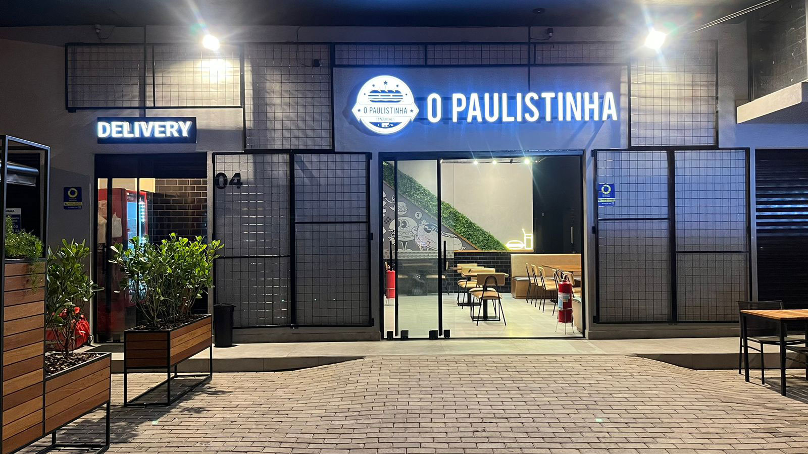 fachada comercial de uma hamburgeria com iluminação e varios materiais